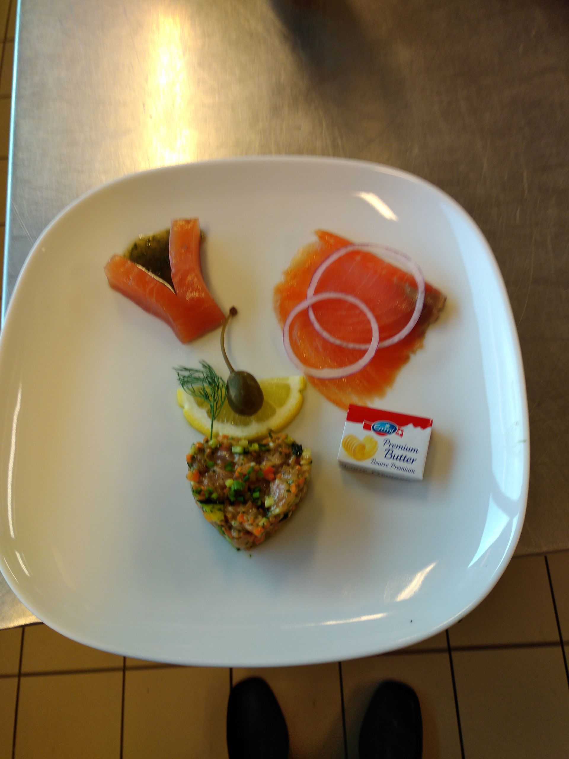 Une assiette blanche garnie d'oignons de saumon fumé et de tranches de citron