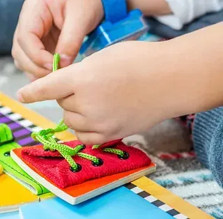Un niño está jugando con un juguete de cordones sobre una mesa.