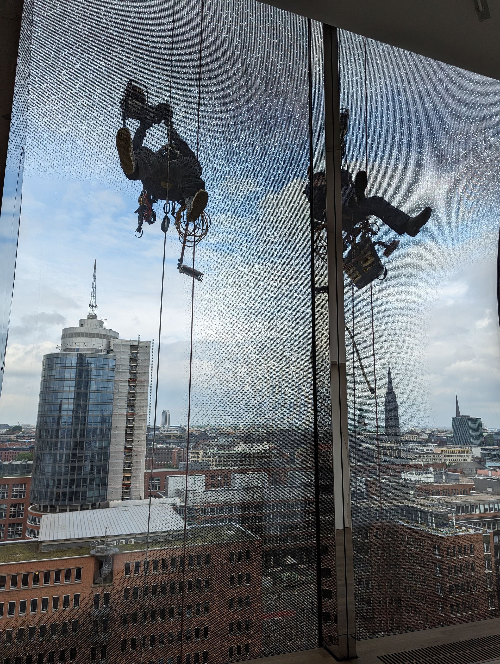 Zwei Fensterputzer hängen an der Elbphilharmonie