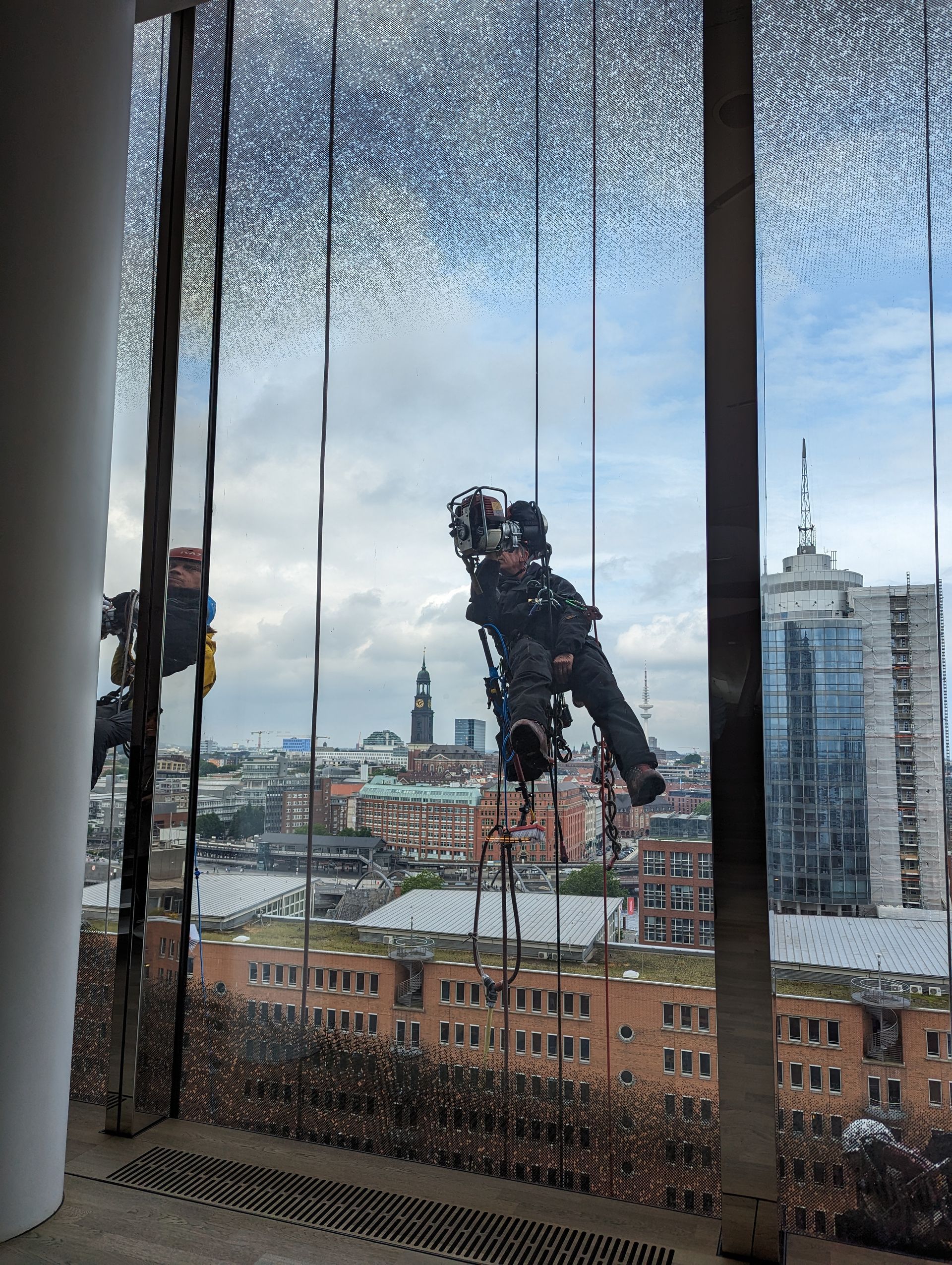 Zwei Fensterputzer hängen an der Außenseite der Elbphilharmonie.