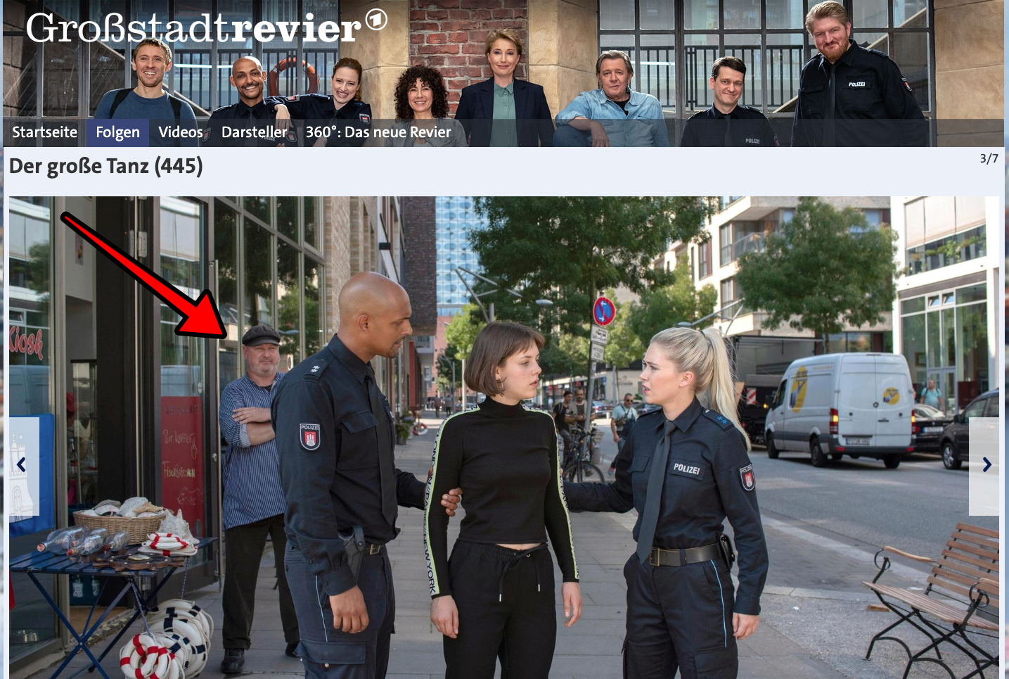 Zwei Polizisten mit einer Frau auf einer Straße in der Stadt; im Hintergrund ein älterer Mann.