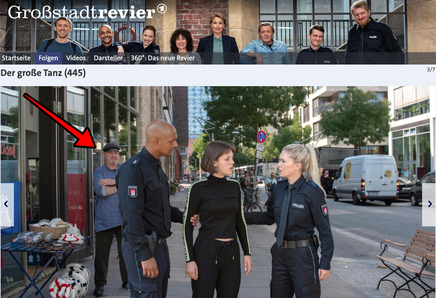 Polizisten, eine Frau und ein Mann auf einer Straße in der Stadt. Ein Mann mit einer Kappe steht in der Nähe.