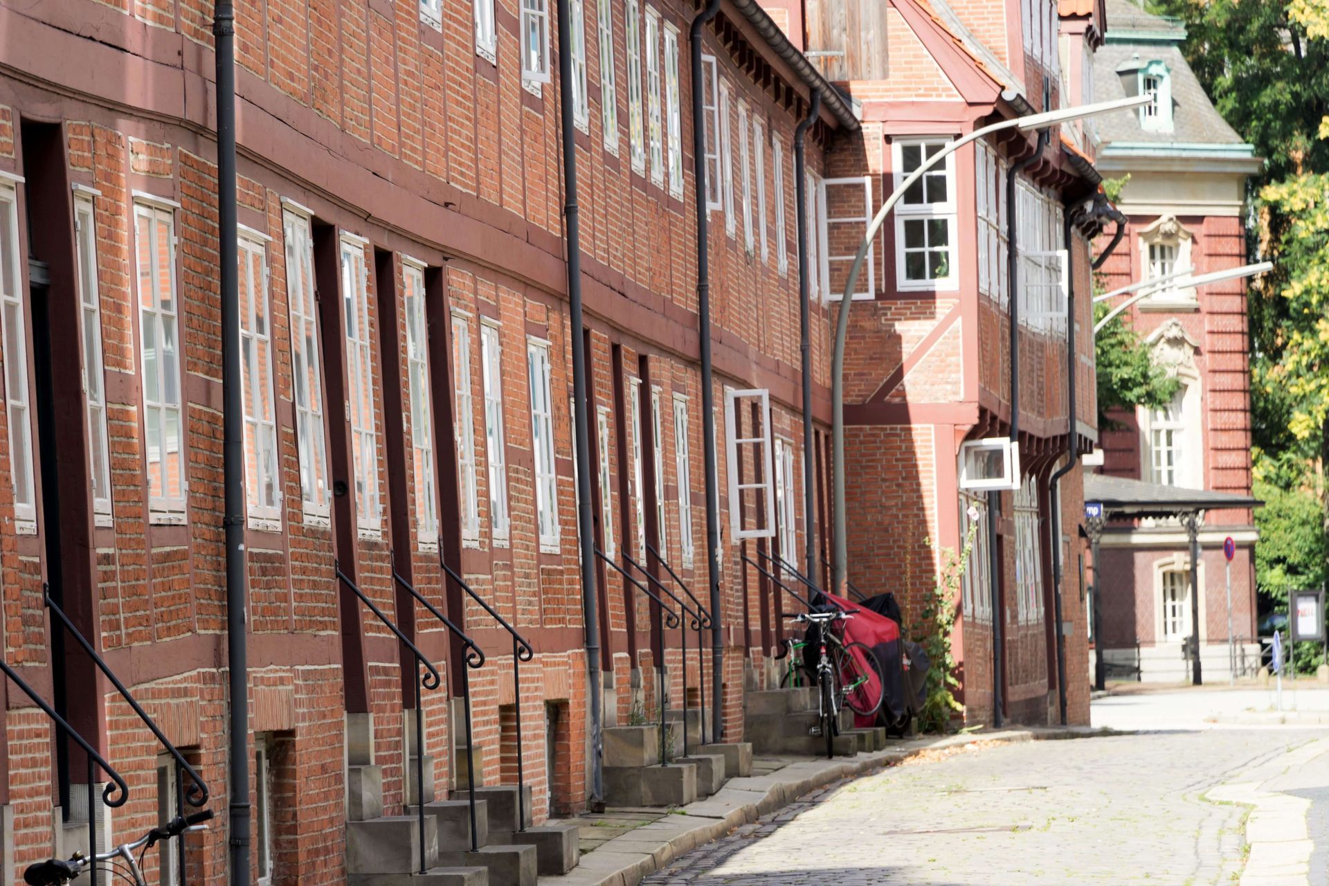 Backsteingebäude mit weiß gerahmten Fenstern; eine Treppe mit schwarzem Geländer; Fahrräder.