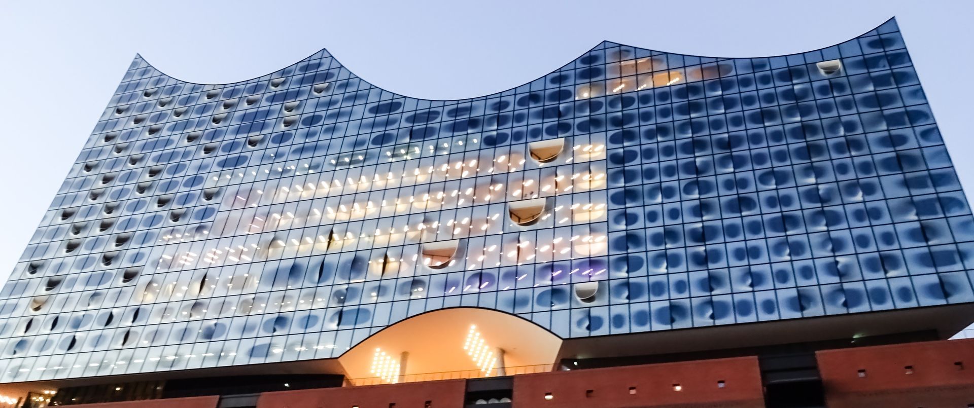 Elbphilharmonie Hamburg building with a glass facade, illuminated at dusk.