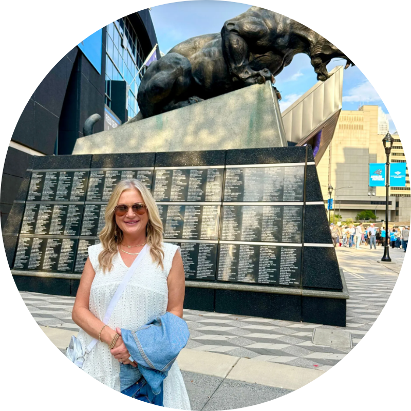 A woman in a white dress is standing in front of a statue of a panther.