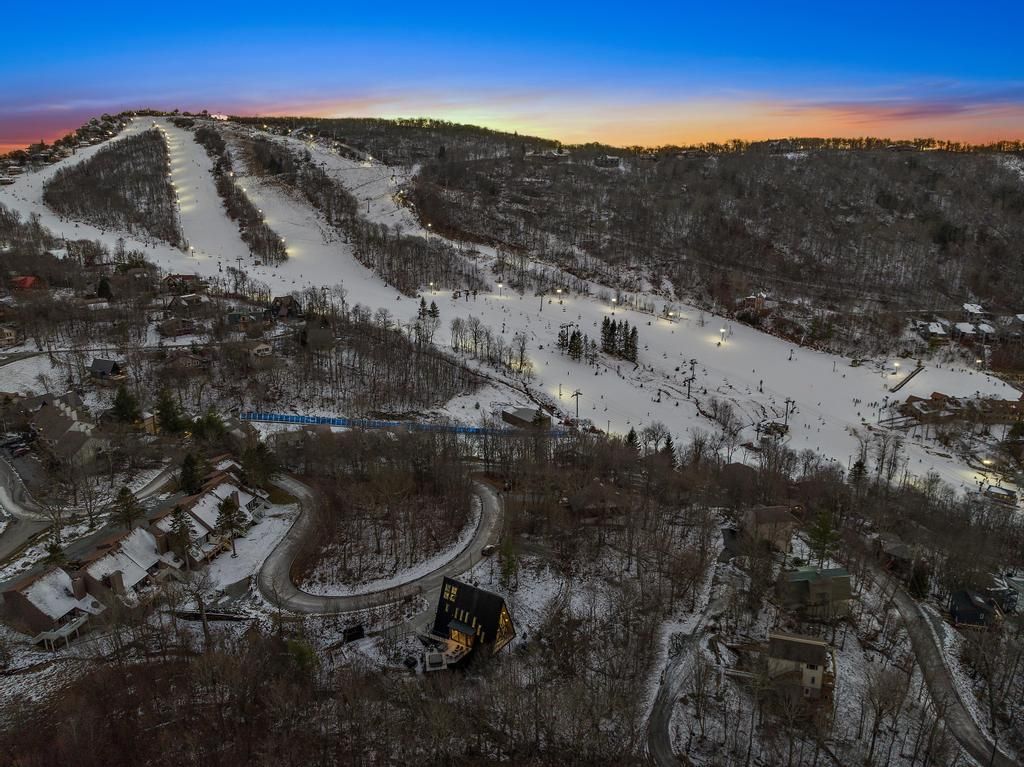 An aerial view of a ski resort at night with a house in the foreground.