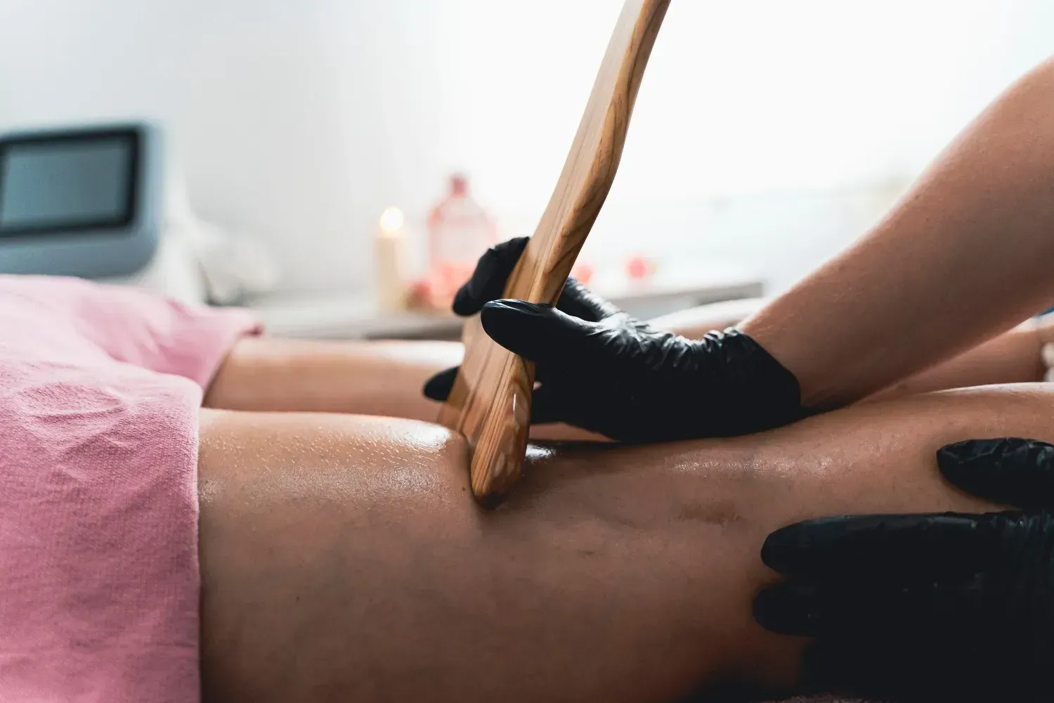 En un entorno clínico, un profesional que lleva guantes negros utiliza una herramienta de madera.