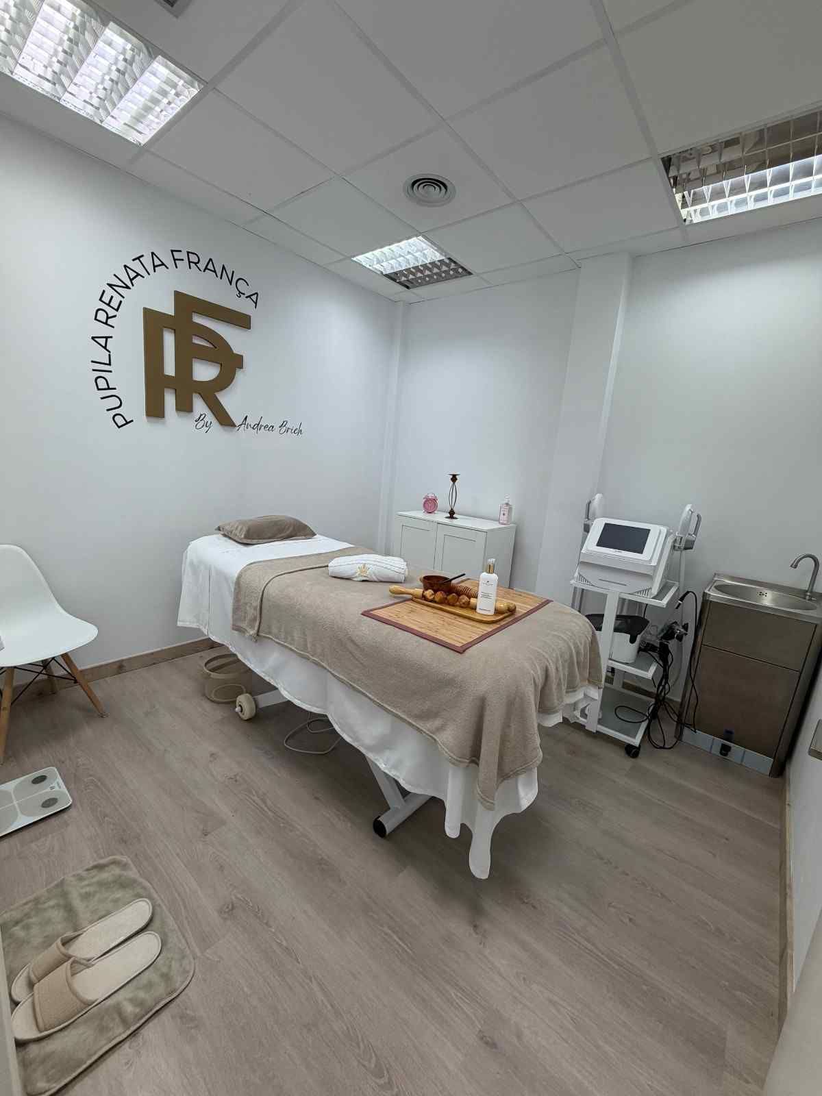 Una sala de spa limpia y de tonos neutros, equipada con una camilla de masaje, aparatos especializados.