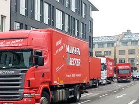Eine Reihe roter Lastwagen fährt eine Stadtstraße entlang.