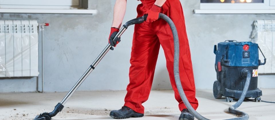 Person saugt Fußboden mit einem Staubsauger