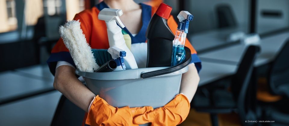 Putzkraft hält einen Eimer mit Putzmitteln