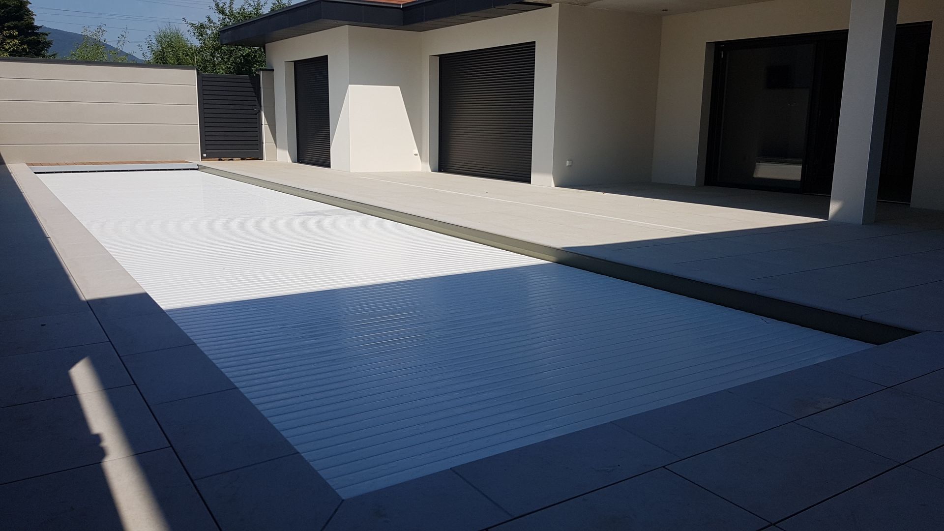 Maison moderne avec terrasse et piscine couverte.
