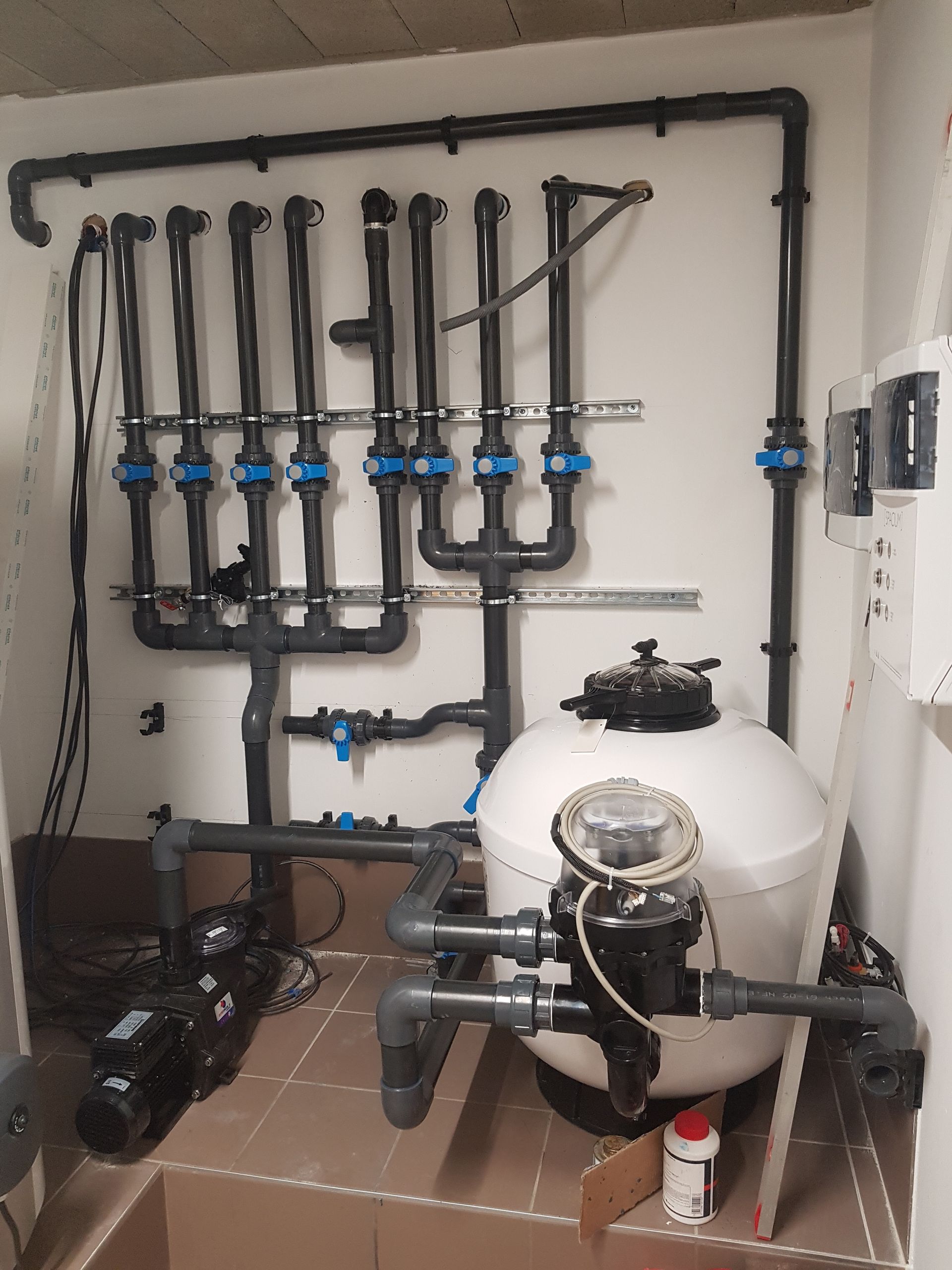 Pompe de piscine et équipement de filtration dans un local technique.