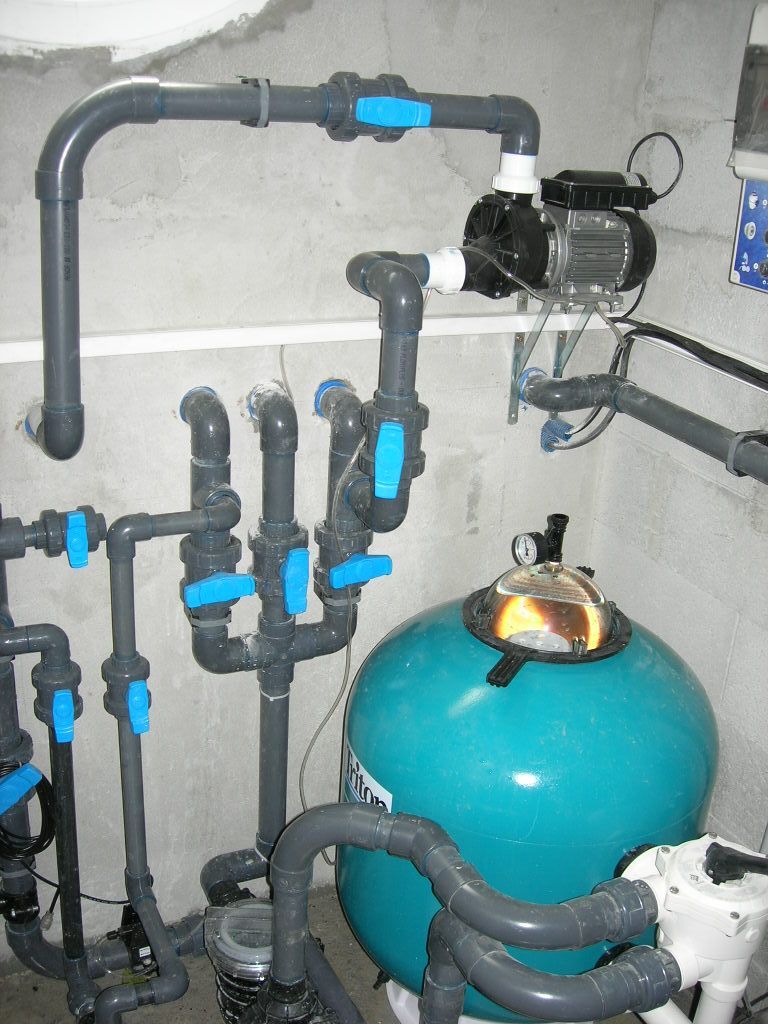 Installation de filtration d’eau avec des tuyaux, des vannes et un réservoir sous pression dans une pièce.