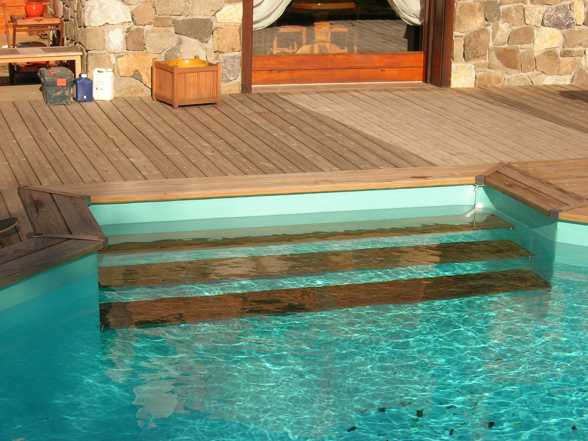 Terrasse en bois avec des marches en bois qui descendent vers une piscine.