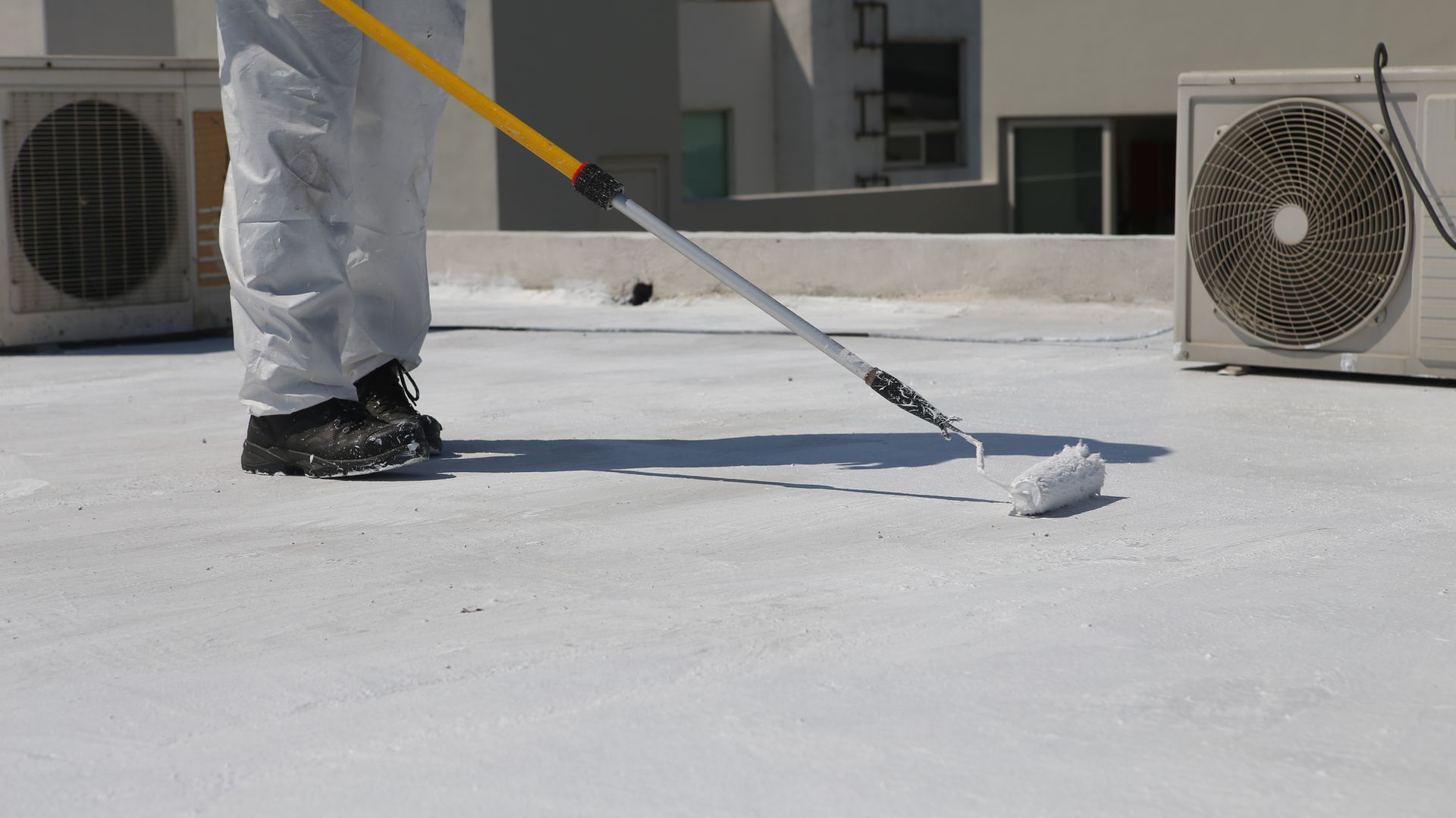 Application d’une peinture blanche sur toiture terrasse au rouleau