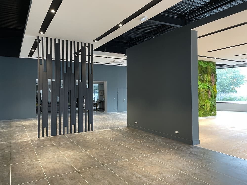 Intérieur de bureau moderne avec un mur d'accent gris foncé, une cloison verticale à lattes et un mur végétal.