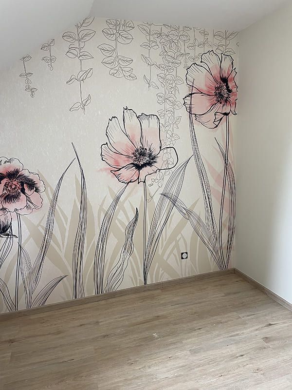 Papier peint orné de grandes fleurs roses dessinées au trait, avec de hautes feuilles vertes, sur un mur couleur crème clair.