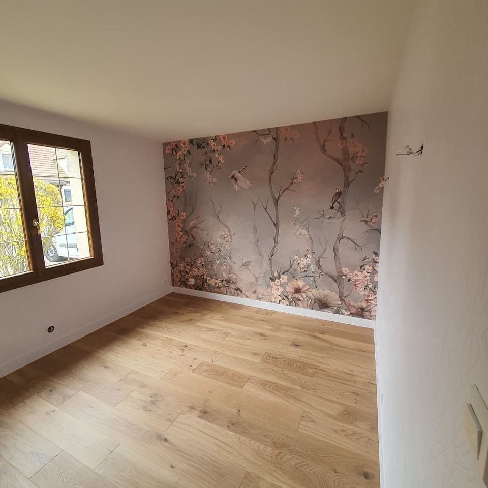 Une pièce avec un parquet clair, des murs blancs unis et un mur d'accent à motifs floraux sur fond brun clair.