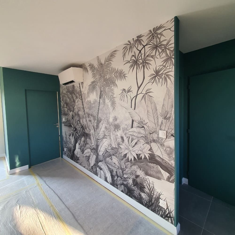 Une pièce ornée d'une fresque murale en papier peint à motif de jungle en noir et blanc, flanquée de murs et de portes peints en vert foncé.
