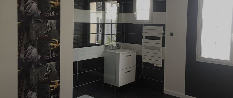 Une salle de bains moderne avec des murs à rayures noires et blanches, une douche vitrée, un meuble-lavabo blanc et un sèche-serviettes.