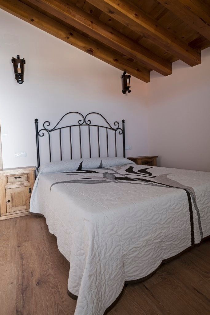 Un dormitorio con una cama de matrimonio, una colcha blanca acolchada, un cabecero de metal negro.