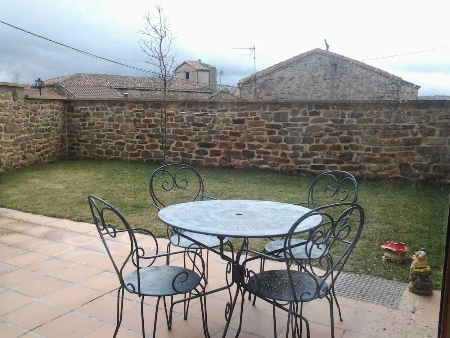 Una mesa redonda de metal estilo bistró con cuatro sillas a juego en un patio embaldosado.