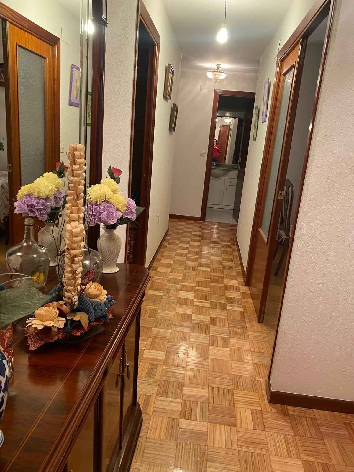 Un pasillo con suelo de parqué de madera, paredes claras.