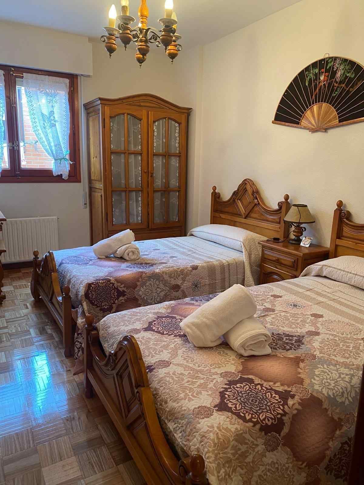 Una habitación de hotel con dos camas individuales con estructura de madera, colchas estampadas.