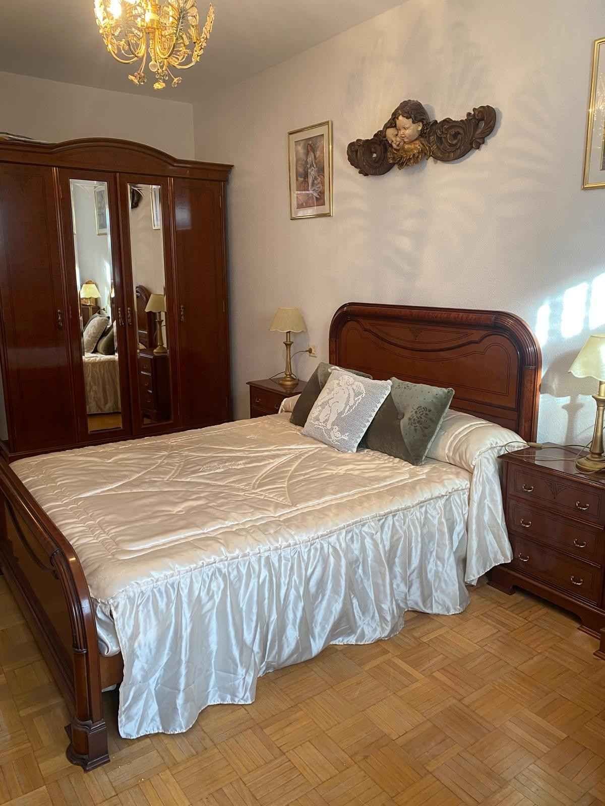 Un dormitorio con una cama de madera con una colcha blanca con volantes.