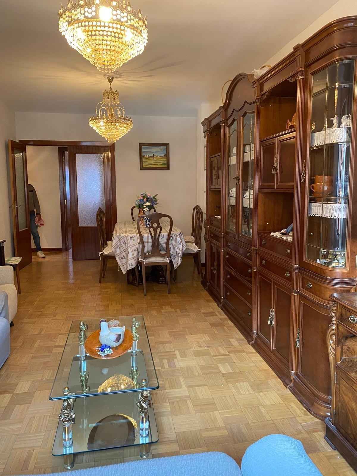 Un comedor y una sala de estar con una gran vitrina de madera, una mesa de centro de cristal.