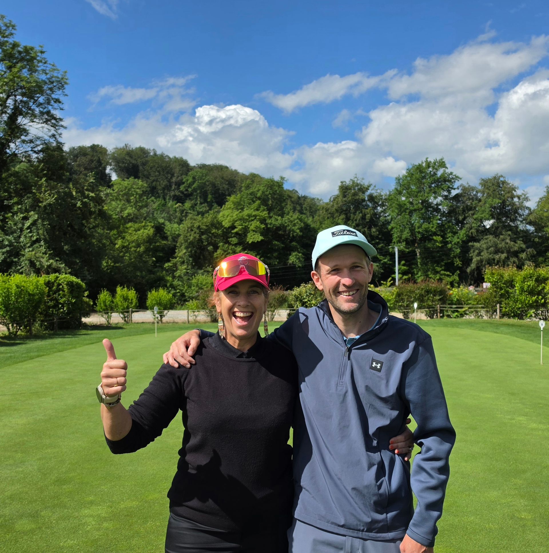 Deux personnes s'entraînent au golf sur un green, balle et club posés sur le gazon.
