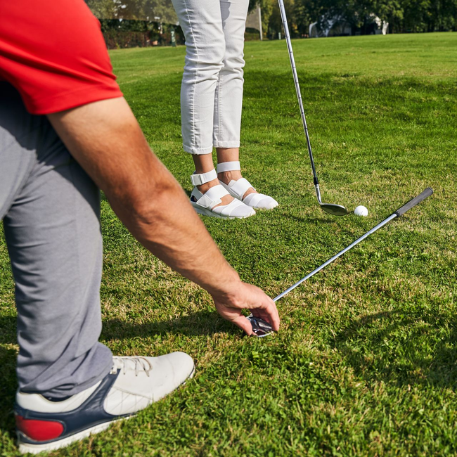 Deux golfeurs s'apprêtent à putter sur le green, une balle de golf se trouvant près du trou.