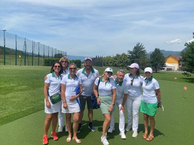 Un groupe de golfeurs pose sur un terrain de golf, vêtus de tenues bleu clair et blanches, par une journée ensoleillée.
