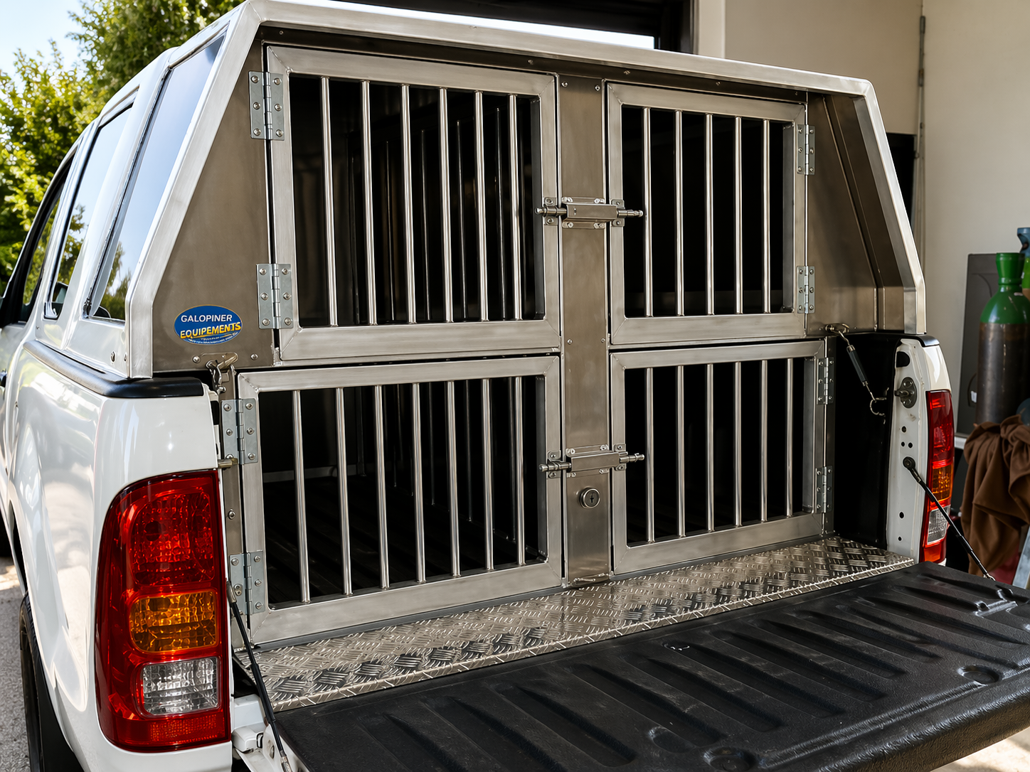 Camionnette avec une caisse de chargement métallique de type chenil dans la benne, garée dans un garage.