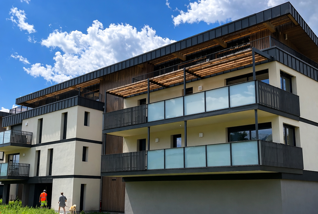 Immeuble moderne à plusieurs étages avec balcons et garde-corps en verre sous un ciel bleu