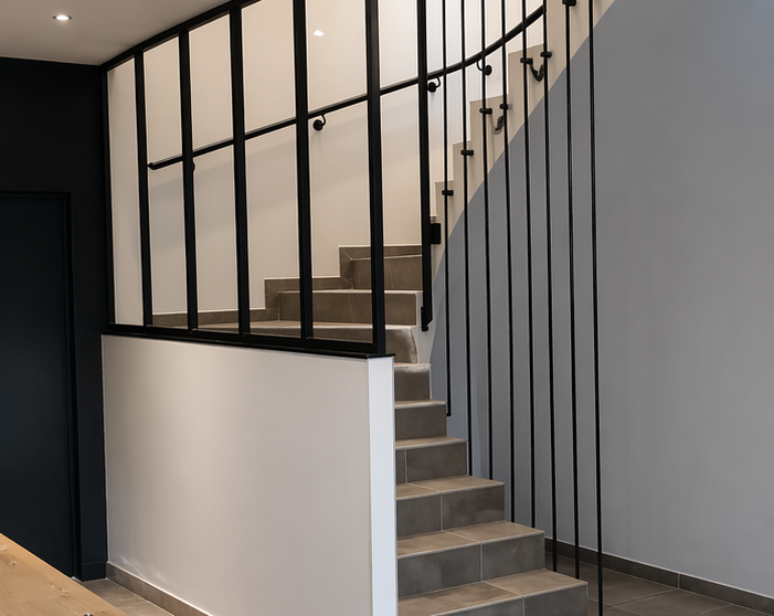 Escalier intérieur moderne avec marches grises, rampe noire et murs blancs dans un couloir minimaliste