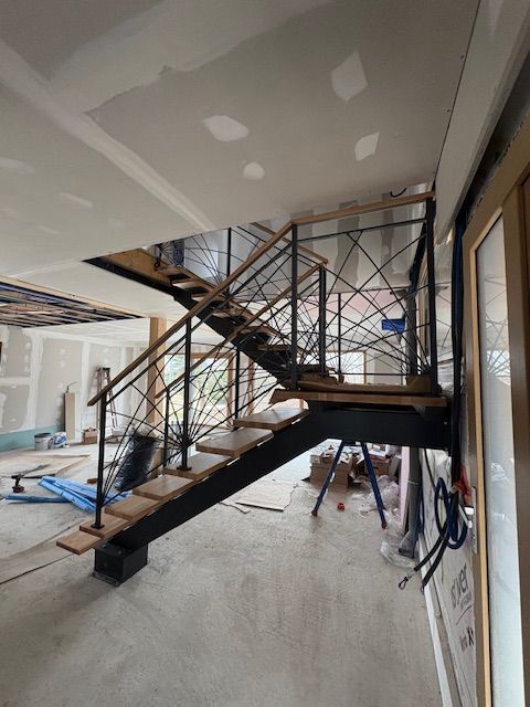 Chantier de construction intérieur avec escalier métallique inachevé et cloisons sèches dans une pièce partiellement rénovée