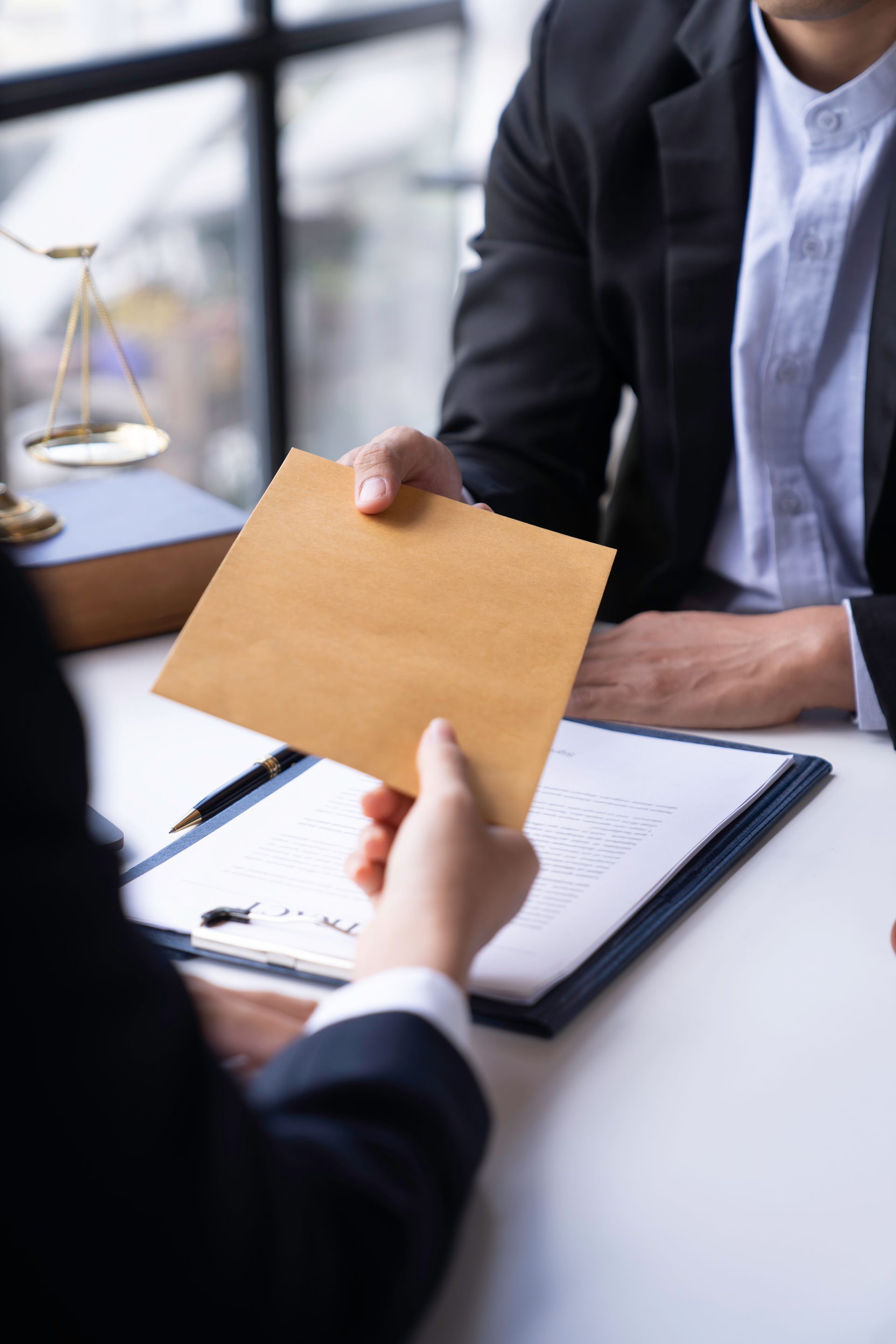 Une personne en costume remet une enveloppe à une autre personne pour lui remettre un document.