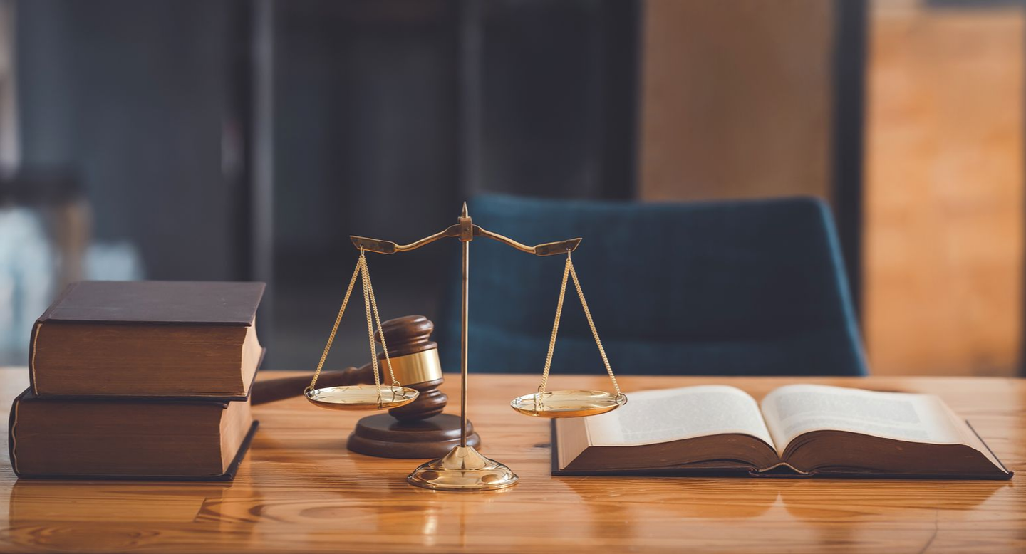 Un maillet, une balance de la justice et des livres de droit sur un bureau en bois.