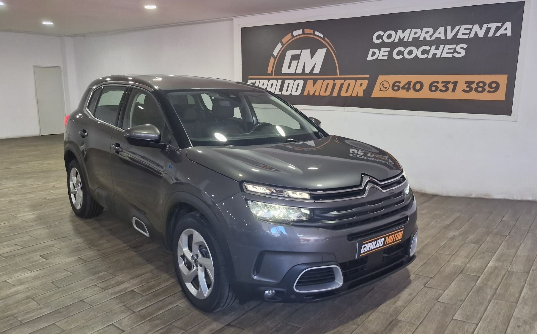SUV Citroën C5 Aircross gris en un concesionario de automóviles, con el logotipo del concesionario y la información de contacto en el fondo.