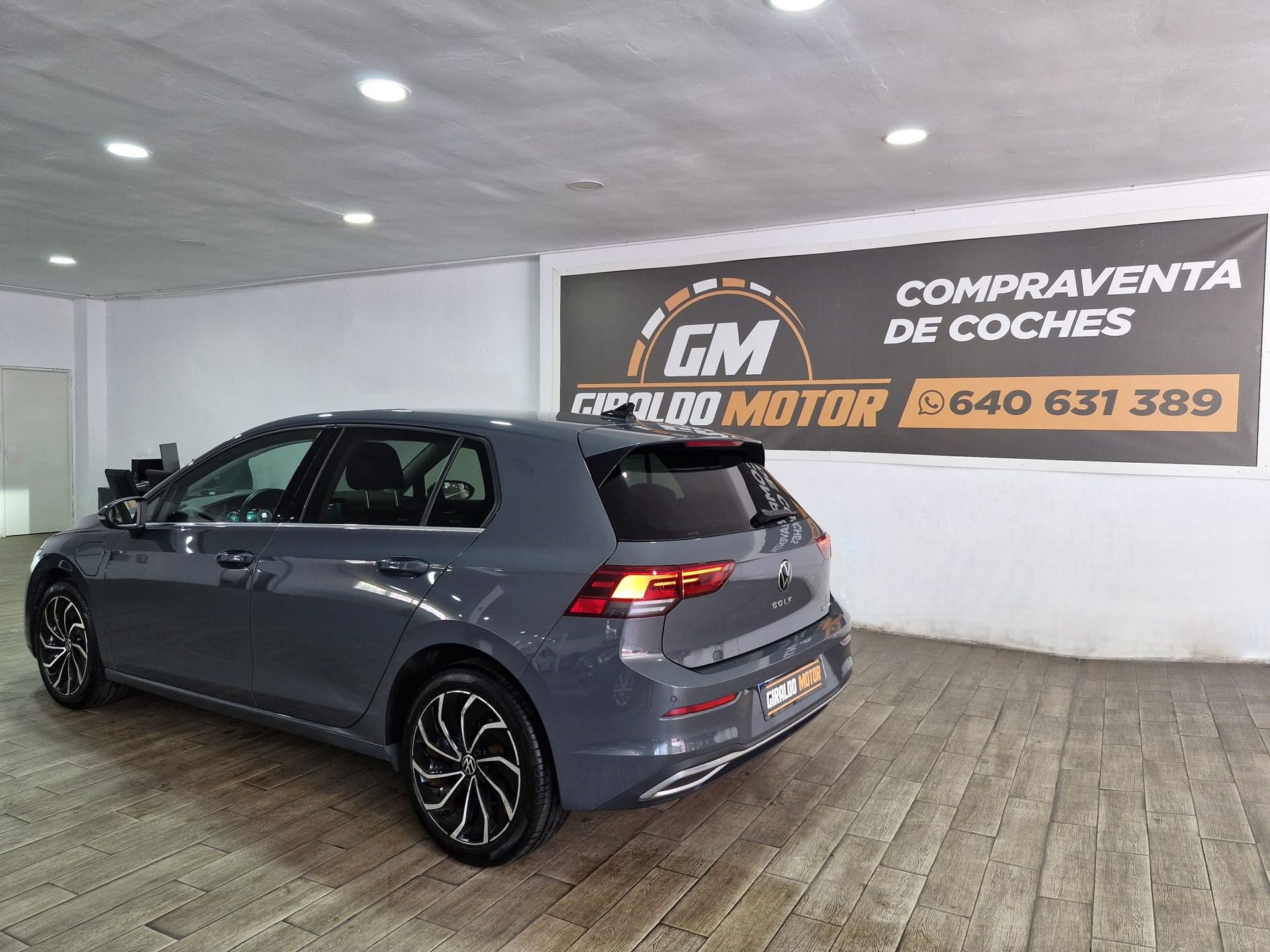 Volkswagen Golf blanco estacionado en un salón de exposición, con ruedas negras y plateadas.