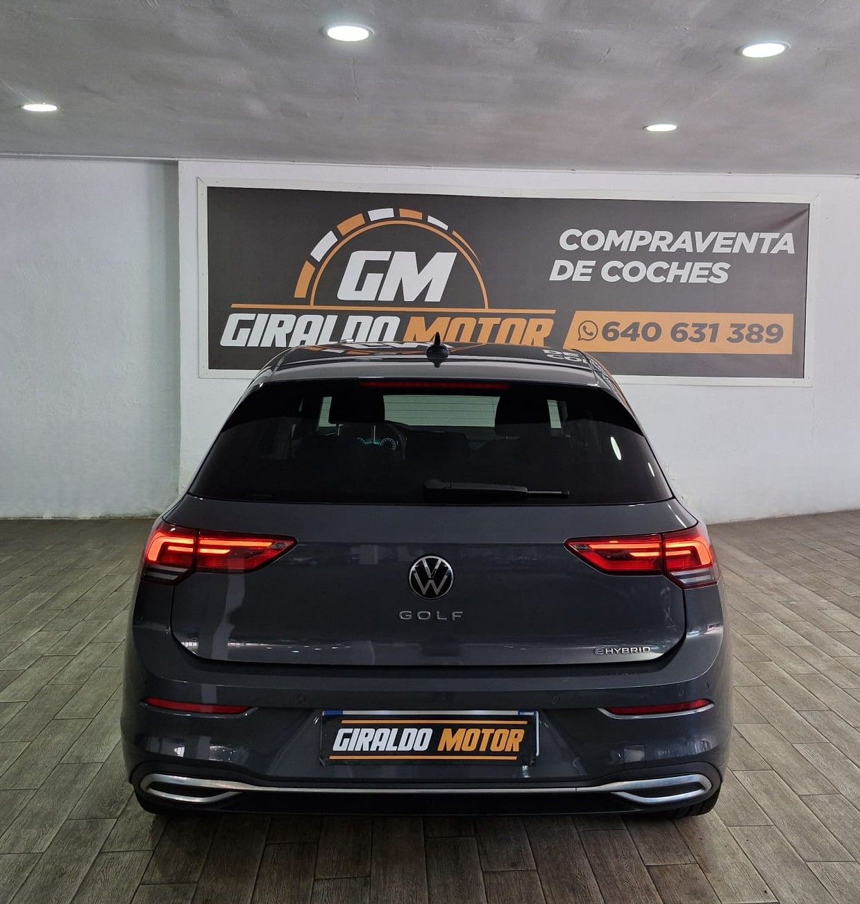 Volkswagen Golf blanco estacionado en un salón de exposición, con ruedas negras y plateadas.
