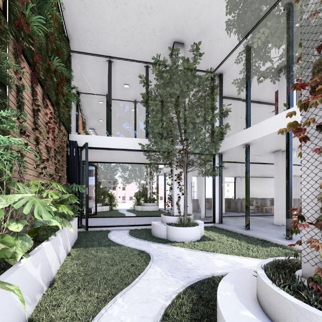 Jardín interior con árbol, pared verde, bancos blancos, paredes de cristal y un camino sinuoso.