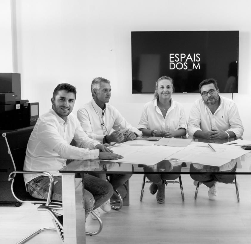 Un grupo de personas sentadas alrededor de una mesa, con un cartel que dice 