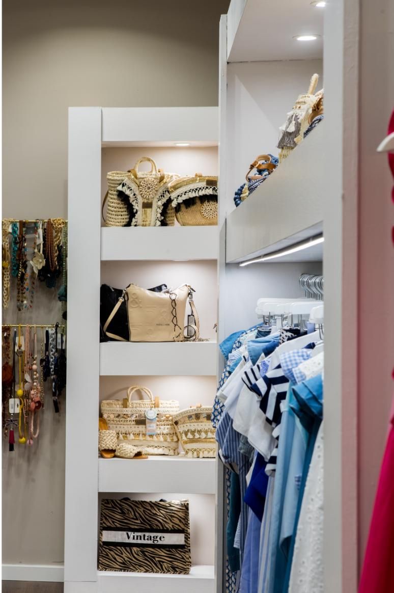 Armario empotrado blanco con estantes para bolsos. La ropa cuelga a la derecha y las joyas a la izquierda.