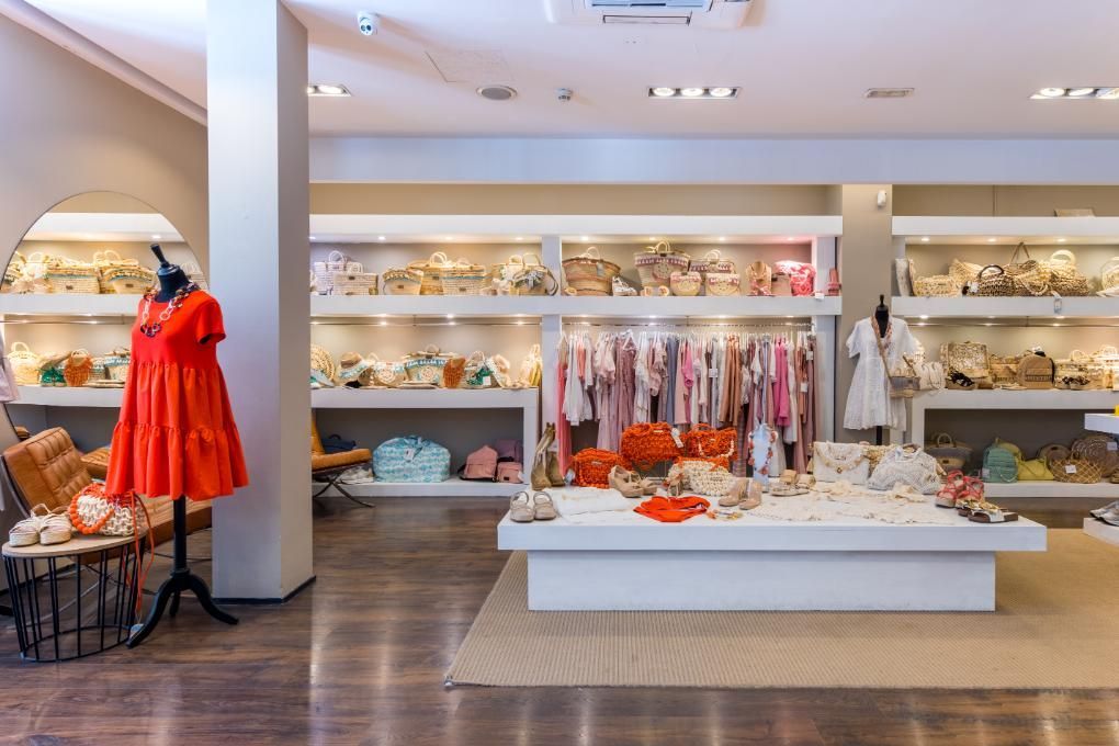 Interior de una tienda de ropa con exhibidores de ropa y un maniquí con un vestido rojo.