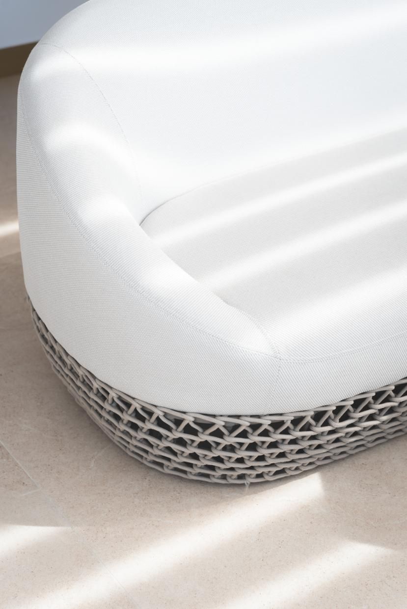 Asiento de exterior acolchado de color blanco con base tejida de color gris.