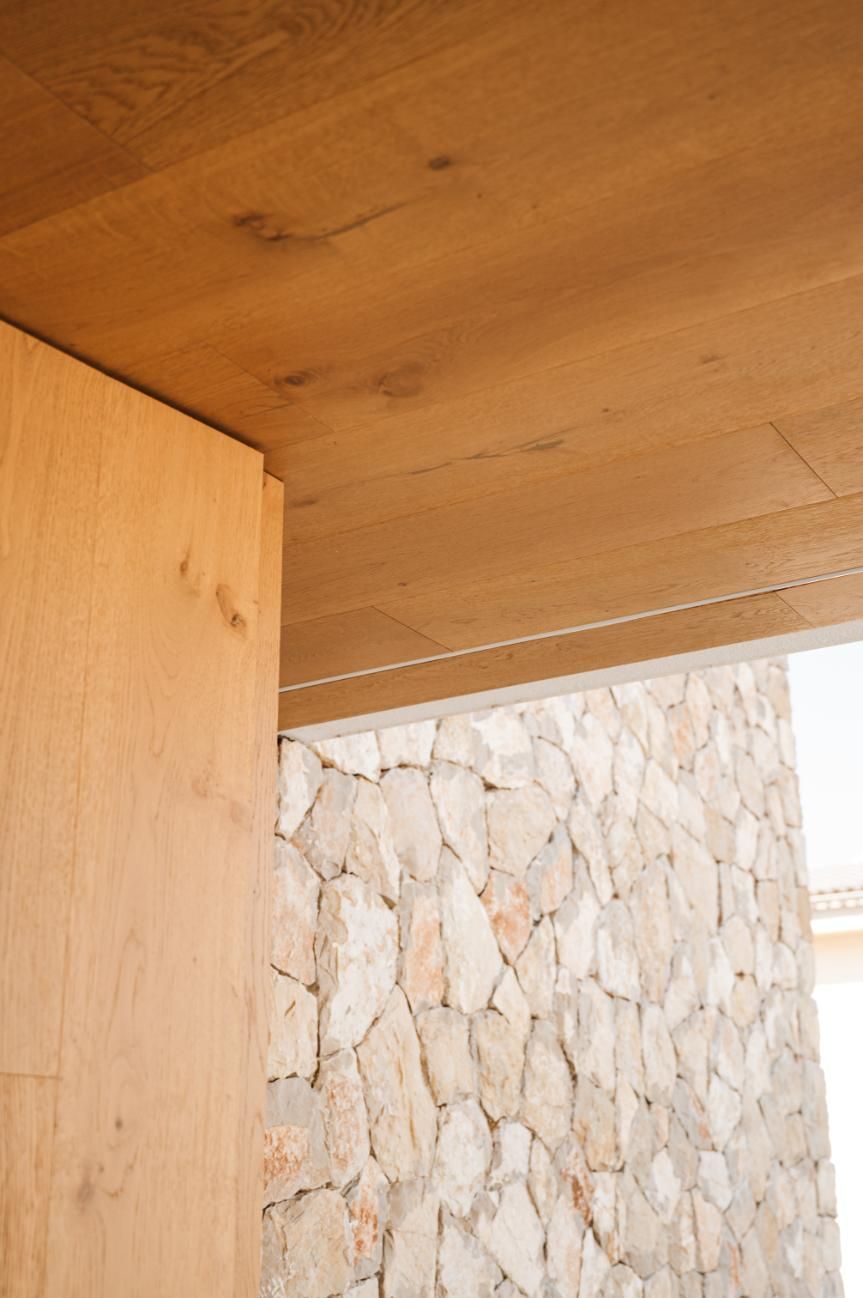 Techo y pared de madera junto a un muro de piedra.