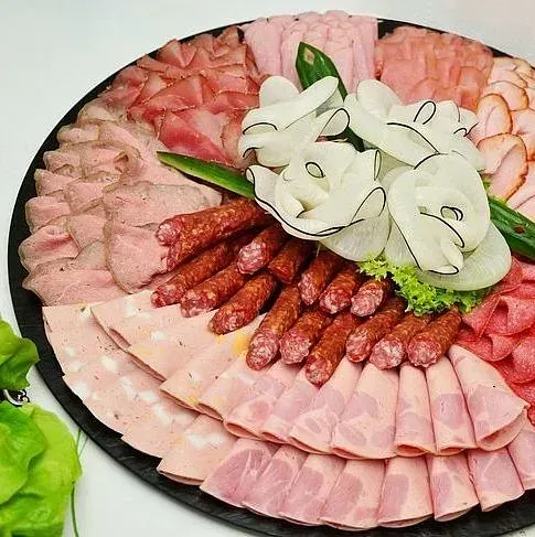 Un plato de carnes y flores sobre una mesa.